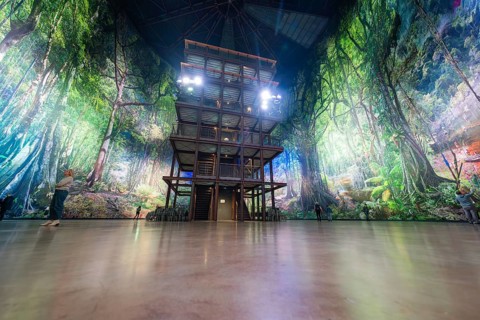 A multi-storey structure in a light-flooded artificial forest background, Amazonia exhibition,
