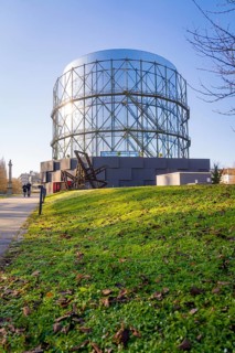 Large steel building in front of a sunny green area, Amazonia exhibition, Gasometer, Pforzheim,