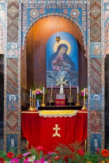 Religious altar with icon and candles richly decorated with flowers in a decorated wall niche,