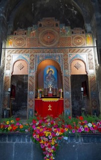 Artfully designed altar in a church, framed by colorful flowers and symbolic images, Sevanavank
