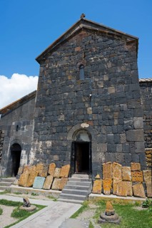 Old stone building with open door and roof under blue sky, cross stones at Sevanavank monastery,