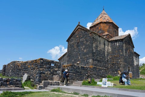 Visitors in front of a historic stone monastery under clear skies, Sevanavank Monastery, Sevan