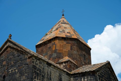 Close-up of a stone church tower with a detailed roof under a blue sky, Sevanavank monastery, Sevan