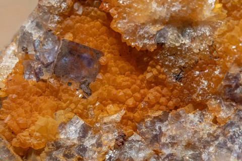 Shiny crystals of blue and orange color can be seen in this mineral formation. They are sparkling