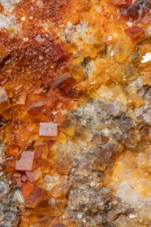 Shiny crystals of blue and orange color can be seen in this mineral formation. They are sparkling