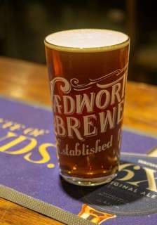 Full pint glass of Wadworth 6X real ale beer on pub bar mat, Wiltshire, England, UK