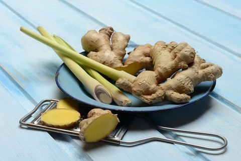 Ginger tubers and lemongrass on plate, grater with ginger pieces