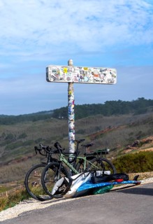 Sticker-covered sign with bicycles and surfboards, Nazaré, Portugal