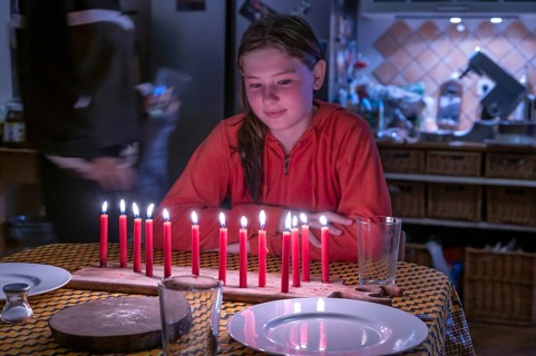 Young girl sitting at the table in front of her thirteen burning birthday candles, Othenstorf,
