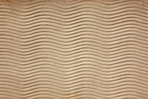 Beige sand surface with uniform wavy lines