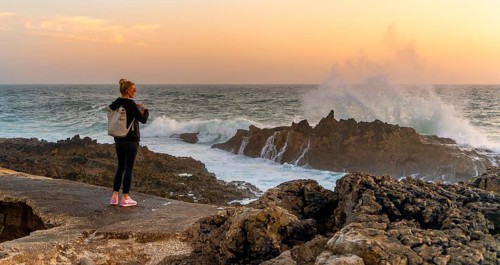 Young tourist standing on the coast of Farol de Cabo Raso lighthouse, SÃ£o Bras de Sanxete