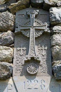 Historic stone cross with engravings and decorated architecture embedded in a stone wall, Chapel of