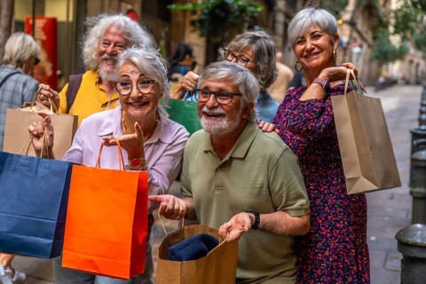 Happy group of smiling senior friends holding shopping bags while enjoying a leisure day out in the