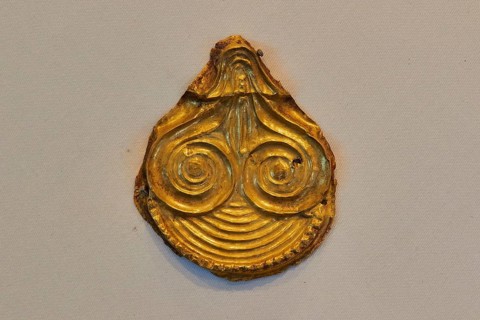 Golden ancient artifact with spiral pattern in teardrop shape, Archaeological Museum, Nemea,