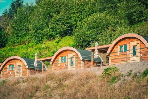Three cozy wooden huts in a green setting give a feeling of relaxation