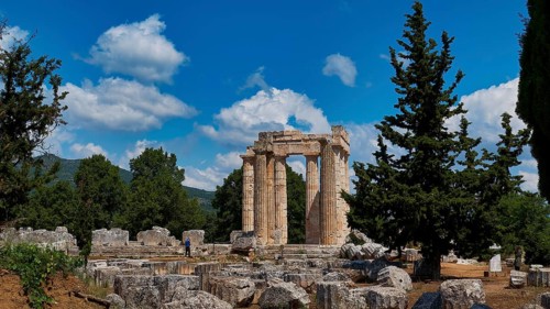 Ancient ruins of a temple surrounded by pine trees and bright blue sky, Ancient Sanctuary of Zeus,