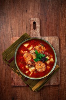 Souzi soup. Georgian dish, meat with oats, tomato sauce and herbs, on a wooden table