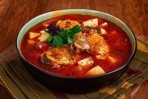 Souzi soup. Georgian dish, meat with oats, tomato sauce and herbs, on a wooden table