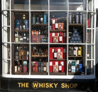 Shopfront window display The Whisky Shop store, Cathedral Close, Exeter city centre, Devon,