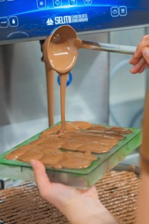 Hand pouring warm chocolate from a ladle into chocolate molds, Christmas baking, Haselstaller Hof,
