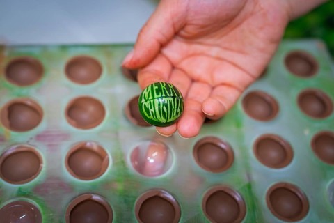Hand holding green chocolate candy with Merry Christmas inscription out of a mold, Christmas