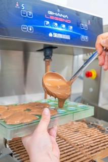 Hand holding green chocolate mold and pouring liquid chocolate with a spoon, Christmas baking,