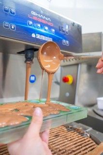 A ladle pours chocolate from a machine into green chocolate molds, Christmas baking, Haselstaller