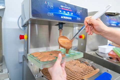 Chocolate is poured into molds from a machine with a ladle, Weihnachtsbacken, Haselstaller Hof,