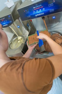 Person uses a blue tool to fill chocolate into a mold at a tempering machine, Christmas baking,