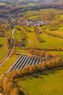 Large-scale solar plant in rural landscape near a village and roads, construction of a PV open-air