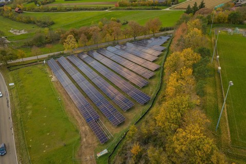 Solar system on a green area with autumn trees in the background, Bau PV Freifaechenanlage, Weil