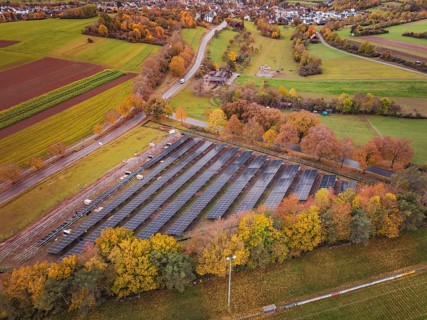 Large-scale solar plant near a village, surrounded by autumnal fields, Bau PV Freifaechenanlage,