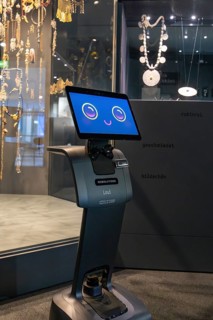 Robot with smiling display stands in front of a jewelry exhibition in the museum, robot personality