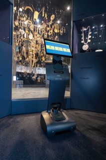Robot with display stands in front of impressive jewelry exhibition in the museum, robot