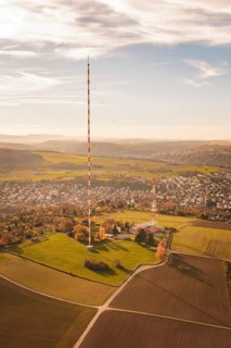 A tall radio tower rises above an autumn landscape with a small town in the background, MÃ¼hlacker,