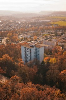 A high-rise residential building rises between autumn trees in an urban area, MÃ¼hlacker, Enzkreis,
