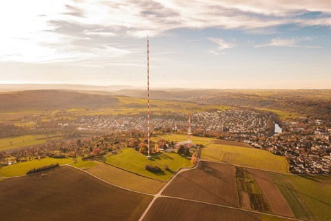 A radio tower stands in the middle of a vast, autumnal landscape next to a village, MÃ¼hlacker,