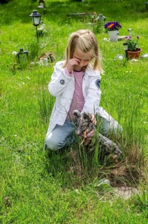 Grieving blonde 7-year-old girl at her dog's grave at pet cemetery in Ystad, SkÃ¥ne County, Sweden,