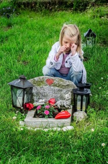 Grieving blonde 7-year-old girl at her cat's grave at pet cemetery in Ystad, SkÃ¥ne County, Sweden,
