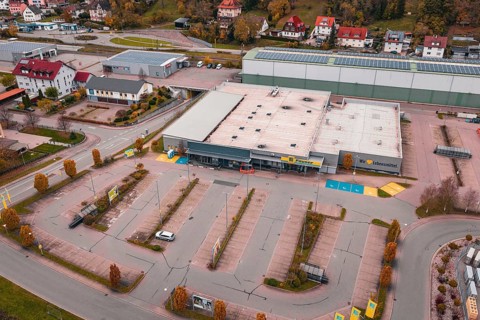 Large supermarket with adjacent parking lot and surrounding residential buildings in an autumn city