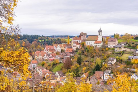 Panorama of a traditional town with church tower, surrounded by autumn landscape and fields,