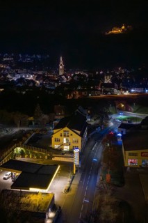 Nighttime city view with illuminated gas station, castle on hill in the distance, Nagold, Calw