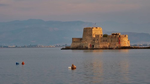 Bourtzi island fortress, tranquil water landscape with a historic castle and buoys in the evening