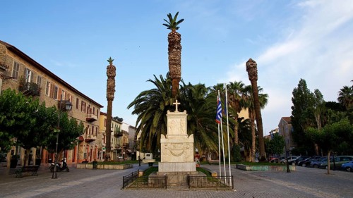 Old town of Nauplion, monument surrounded by palm trees and flags on a cozy town square, Nauplion,