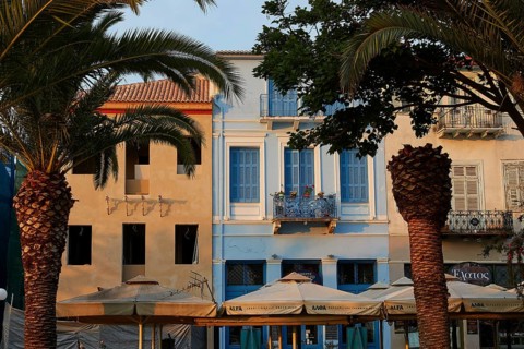 Old town of Nauplion, house facades with palm trees and cafés in a Mediterranean evening mood,