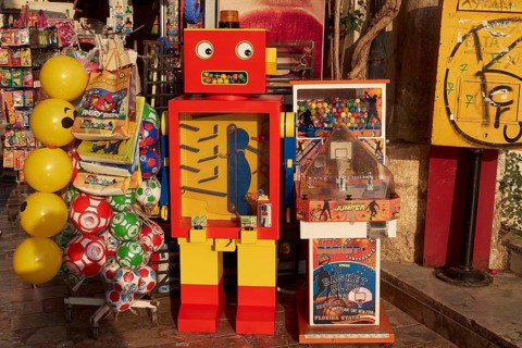 Old town of Nauplion, A colorful robotic toy machine next to yellow balloons at a street stand,