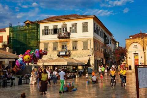 Old town of Nauplion, lively town square with cafés, people, bicycles and colorful balloons at