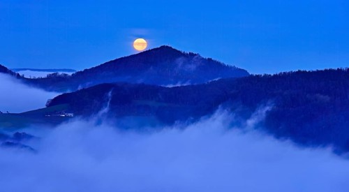 View from the Gisliflue of the Jura foothills of Strihen, covered in fog, in the light of the full