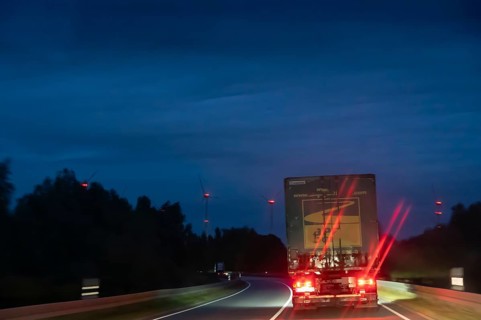 Truck on federal highway at night, wind turbine lights on the left, Schleswig-Holstein, Germany