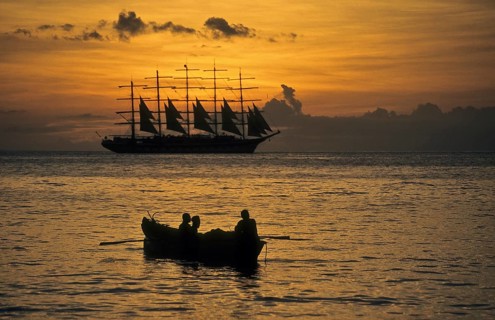 Romantic view of the Caribbean Sea during sunset In the foreground small fishing boat with three